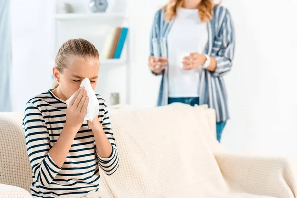 Kid with closed eyes sneezing near mother at home — Stock Photo