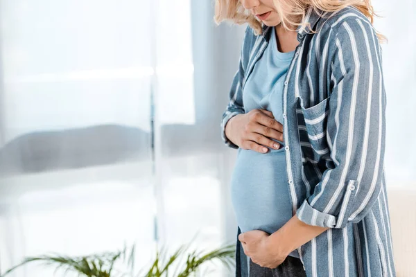 Ausgeschnittene Ansicht einer schwangeren Frau, die ihren Bauch zu Hause berührt — Stockfoto