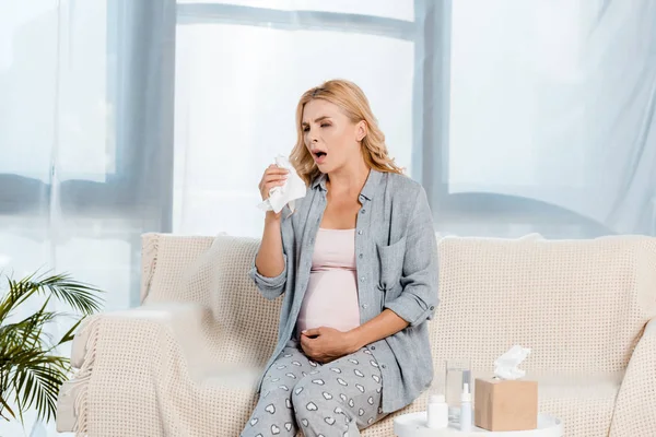 Malade enceinte femme toucher ventre wile éternuer à la maison — Photo de stock
