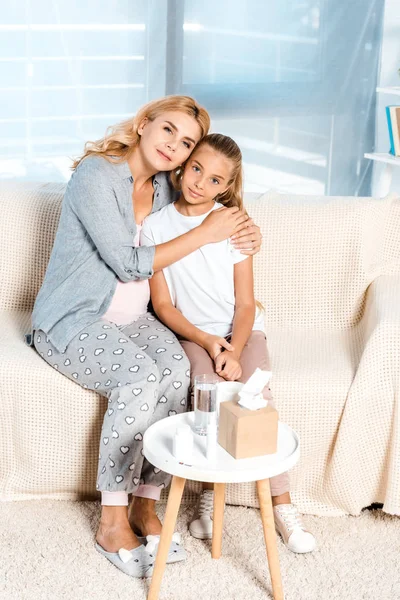 Pregnant mother hugging daughter near table with tissue box — Stock Photo