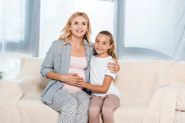 Figlia felice commovente pancia di madre incinta a casa — Foto stock