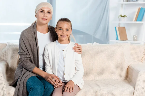 Хвора мати сидить на дивані з щасливою дочкою — стокове фото
