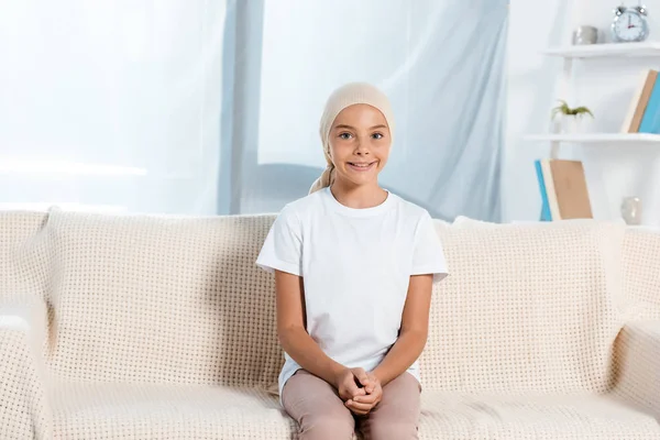 Heureux enfant en foulard assis sur le canapé dans le salon — Photo de stock