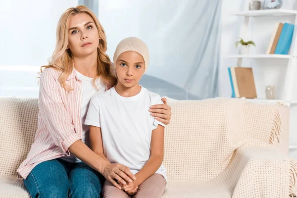 Traurige Mutter sitzt mit kranker Tochter auf Sofa — Stockfoto