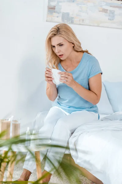 Selective focus of woman holding cup with tea while sitting on bed — Stock Photo