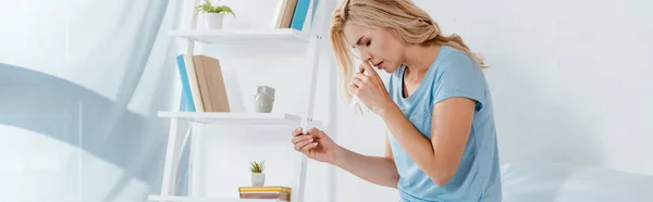 Panoramaaufnahme einer kranken Frau, die Nasenspray in der Hand hält, während sie die Nase berührt — Stockfoto