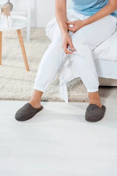 Vista recortada de la mujer sosteniendo termómetro digital en casa - foto de stock