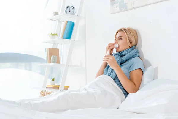 Donna malata che tiene il tessuto vicino al naso mentre si trova a letto — Foto stock