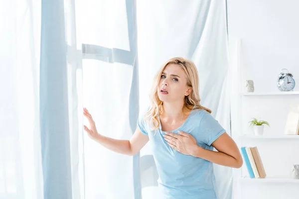 Sick woman touching chest and looking at camera — Stock Photo