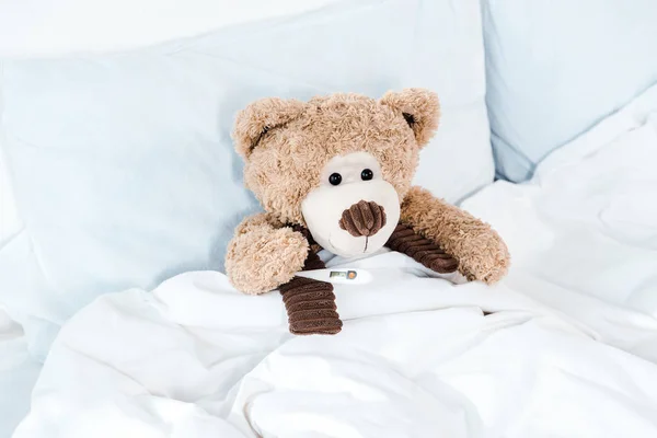 Teddy bear on bed with white bedding and pillows — Stock Photo