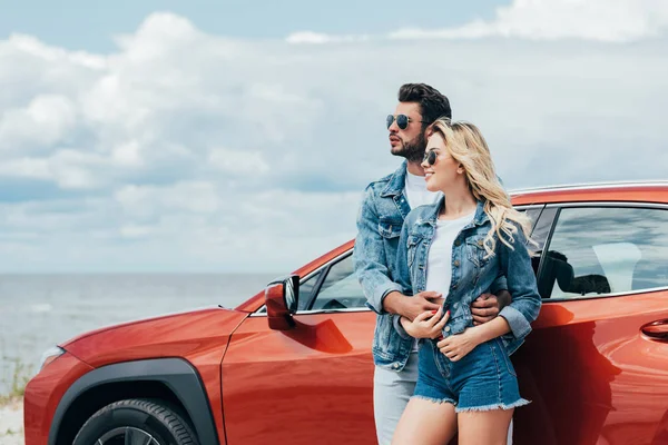 Attraktive Frau und schöner Mann in Jeansjacken, die sich draußen umarmen — Stockfoto