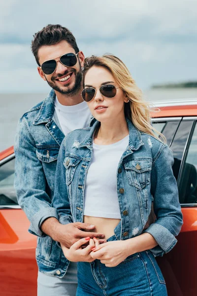 Привлекательная женщина и красивый мужчина в джинсовых куртках обнимаются снаружи — стоковое фото