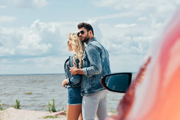 Приваблива жінка і красивий чоловік в джинсових куртках, що обіймаються зовні — стокове фото