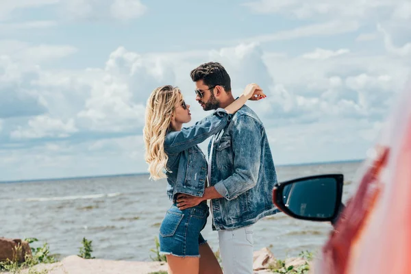 Mulher atraente e homem bonito em jaquetas jeans abraçando fora — Fotografia de Stock