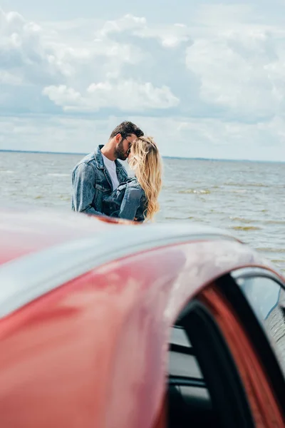 Selective focus of woman and man in denim jackets kissing outside — Stock Photo