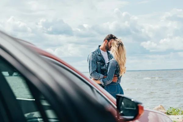 Selective focus of woman and man in denim jackets kissing outside — Stock Photo