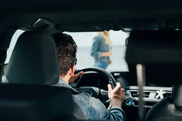 Вид сзади мужчины, сидящего в машине и смотрящего на женщину — стоковое фото