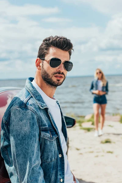 Selektiver Fokus eines gut aussehenden Mannes in Jeansjacke, der in die Kamera blickt — Stockfoto