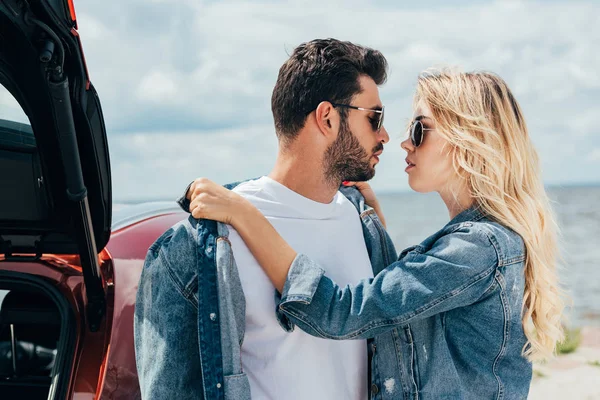 Attraktive Frau und schöner Mann in Jeansjacken, die sich draußen küssen — Stockfoto