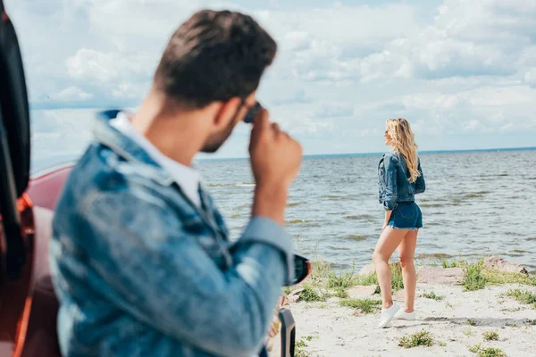 Enfoque selectivo de la mujer rubia en pantalones cortos de mezclilla y chaqueta mirando hacia otro lado - foto de stock