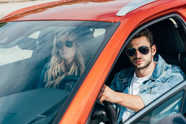 Mulher atraente e homem bonito em jaquetas jeans sentado no carro — Fotografia de Stock