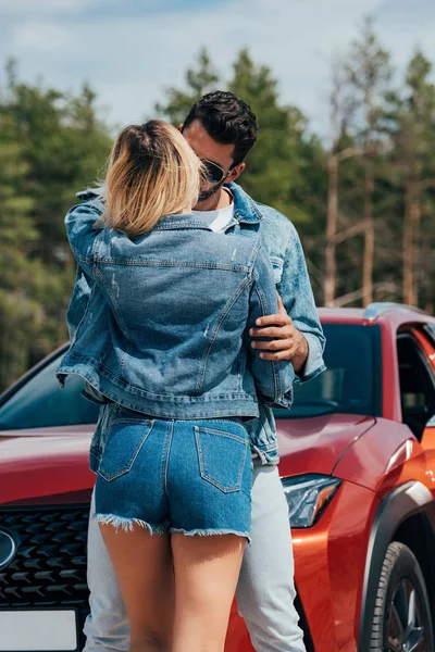 Vista posteriore di donna e uomo in giacche baciare vicino auto — Foto stock