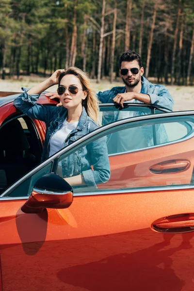 Привлекательная женщина и красивый мужчина в куртках, стоящих рядом с машиной — стоковое фото