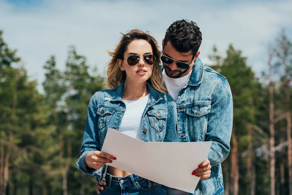 Attractive woman and handsome man in jackets looking at map — Stock Photo