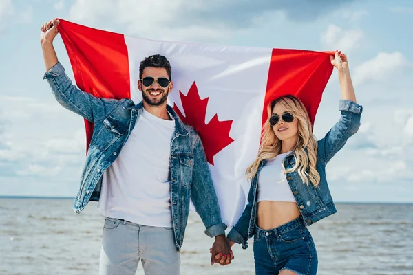 Mujer rubia y hombre de chaqueta con bandera canadiense - foto de stock