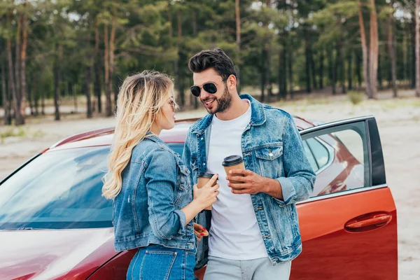 Mulher loira e homem bonito em jaquetas jeans segurando copos de papel — Fotografia de Stock