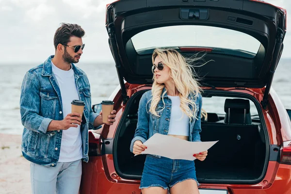 Atraente mulher segurando mapa e bonito homem segurando copos de papel — Fotografia de Stock