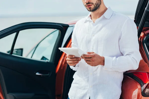 Vue recadrée de l'homme en chemise blanche en utilisant un appareil numérique à l'extérieur — Photo de stock