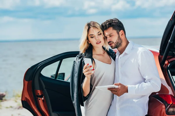 Attraktive Frau mit Smartphone und schöner Mann mit digitalem Tablet — Stockfoto