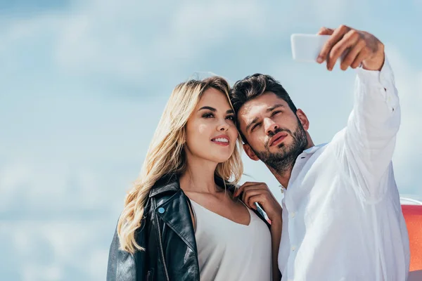 Attractive woman and handsome man smiling and taking selfie — Stock Photo