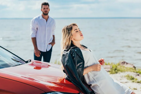 Foyer sélectif de la femme attrayante en robe avec les yeux fermés couché sur la voiture — Photo de stock