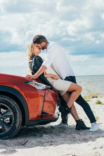 Atractiva mujer y hombre guapo besándose en el coche fuera - foto de stock