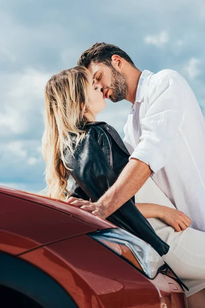 Attractive woman and handsome man kissing on car outside — Stock Photo