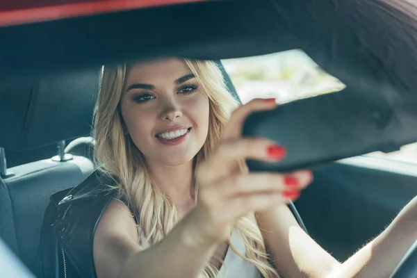 Mujer atractiva y rubia sonriendo y sentada en coche - foto de stock
