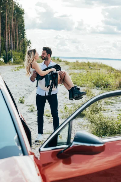 Bonito homem segurando atraente e loira mulher no vestido — Fotografia de Stock