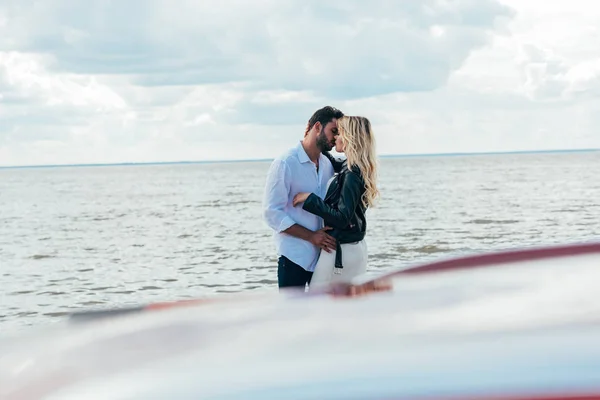 Attractive woman and handsome man hugging and kissing outside — Stock Photo