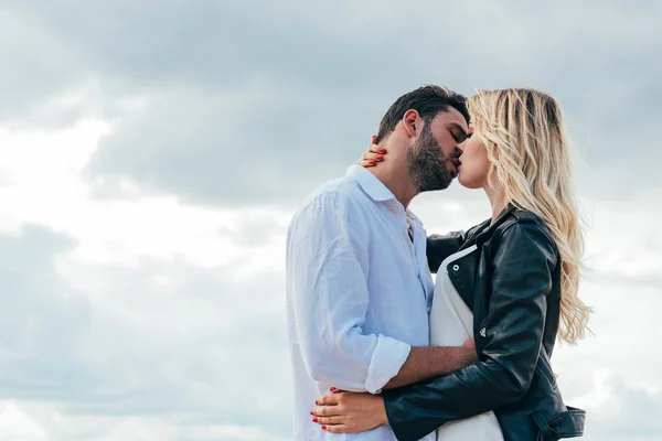 Mujer atractiva y hombre guapo abrazar y besar fuera - foto de stock