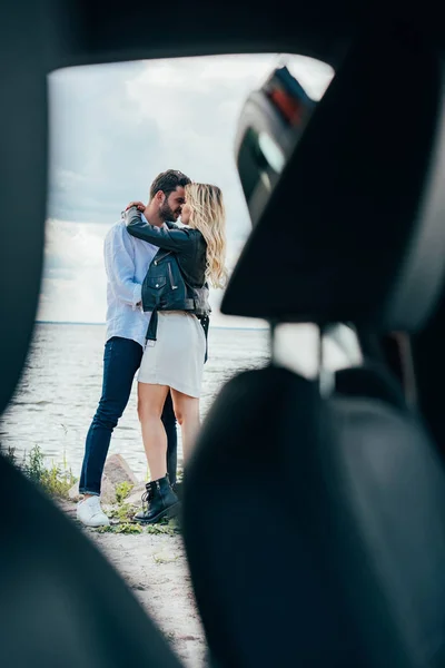 Привлекательная женщина и красивый мужчина обнимаются и целуются снаружи — стоковое фото