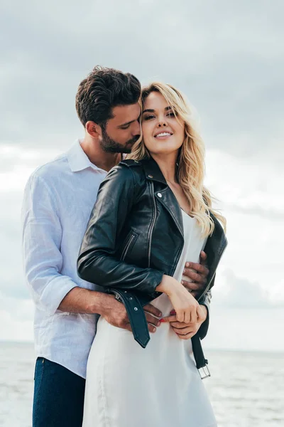 Atractiva mujer y hombre guapo sonriendo y abrazándose fuera - foto de stock