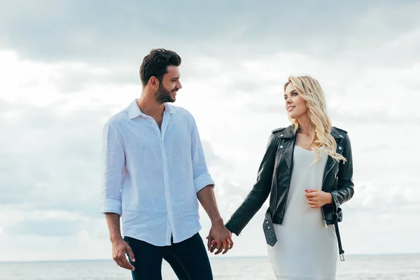 Attractive woman and handsome man smiling and holding hands — Stock Photo