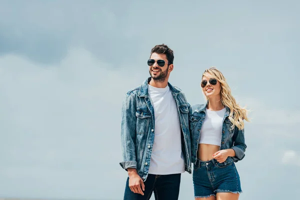 Attraktive Frau und gutaussehender Mann in Jeansjacken, die draußen lächeln und sich umarmen — Stockfoto