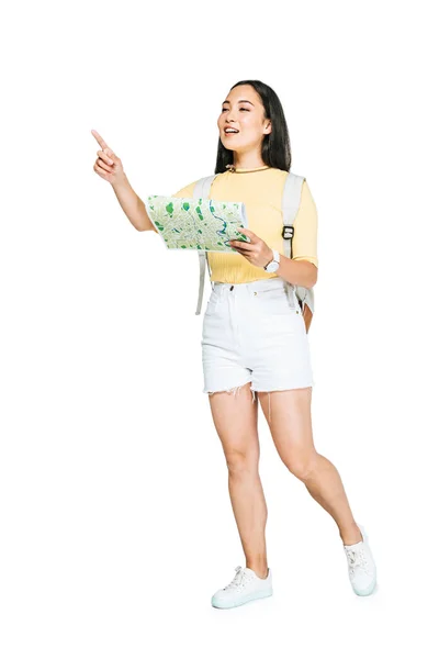 Attrayant asiatique fille regardant loin et pointant du doigt tout en tenant carte sur fond blanc — Photo de stock