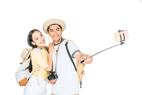 Dos feliz asiático turistas tomando selfie en smartphone con selfie palo aislado en blanco - foto de stock