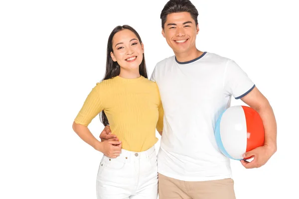 Schöner asiatischer Mann hält Strandball während Umarmung glücklich Freundin isoliert auf weiß — Stockfoto