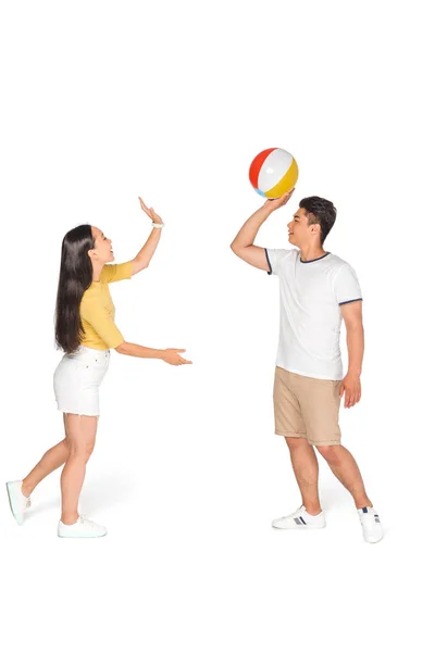 Весёлый азиатский мужчина и женщина играют в пляжный мяч на белом фоне — стоковое фото