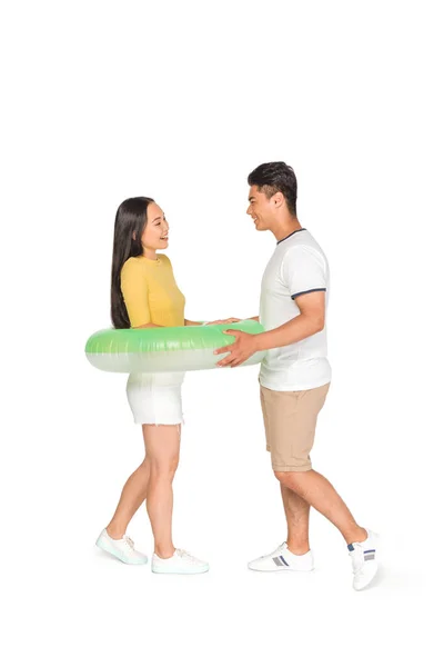 Schöner asiatischer Mann setzt Schwimmring auf fröhliche Freundin auf weißem Hintergrund — Stockfoto